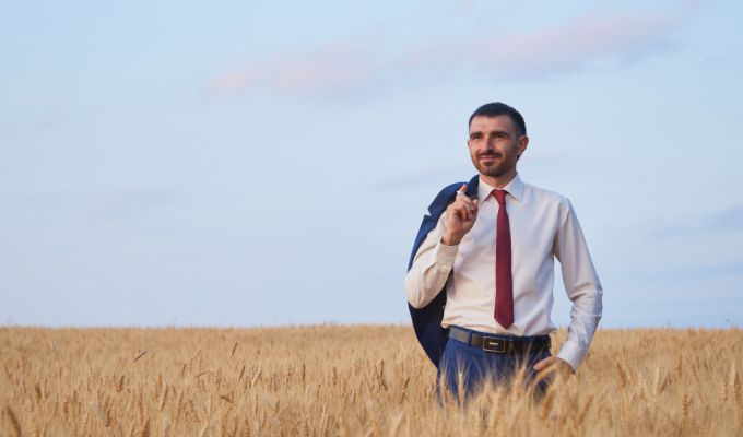 mężczyzna w koszuli i krawacie stoi na polu pszenicy